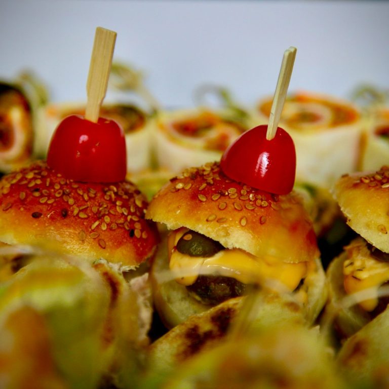 Fingerfood-Platte mit Burgern und Kirschtomaten als Garnitur.