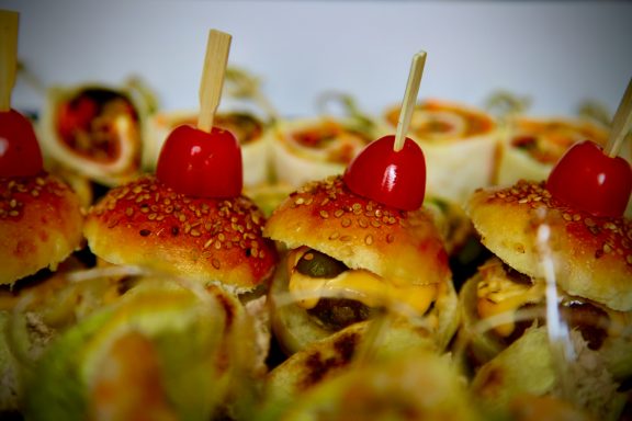 Vorspeisenplatte mit belegten Brötchen und Kirschtomaten obenauf.