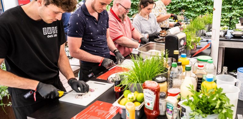 Menschen bereiten in einer Küche Essen mit frischen Zutaten und verschiedenen Saucen zu.