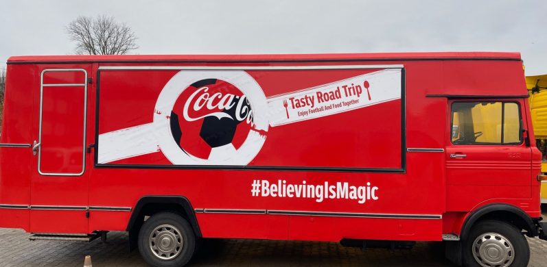 Roter Coca-Cola-Lkw mit großem Logo und dem Slogan "#BelievingIsMagic".